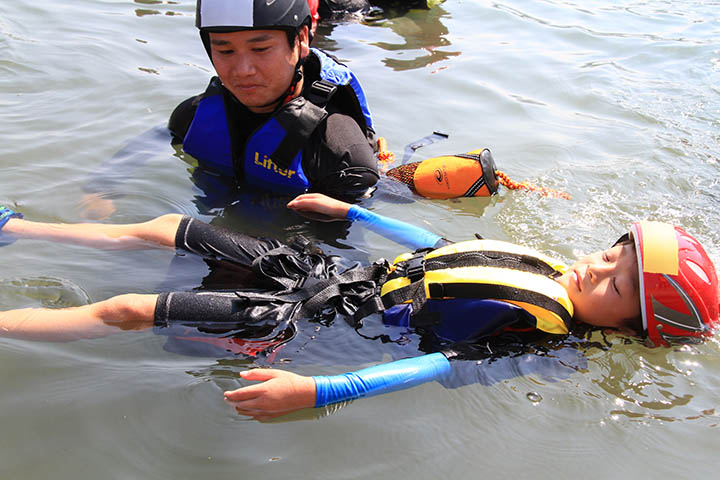 インストラクター指導の下、川に浮く練習をする児童