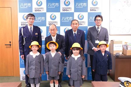 後列左から大楠弘幸八代警察署交通第一課長、北岡教育長、三浦会長、島田和博市民環境部長 前列左から、宮﨑心彩(みいろ)ちゃん、榎田湊太(そうた)くん、松出彩愛(さら)ちゃん、植里隼己(しゅんき)くん