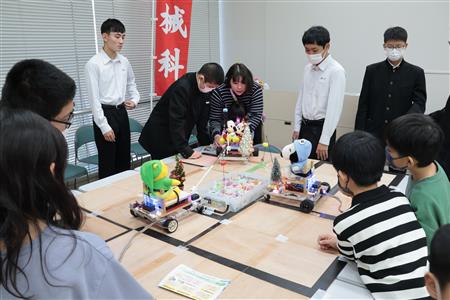 学生たちが作った飴玉を釣り上げる釣りロボットを操作