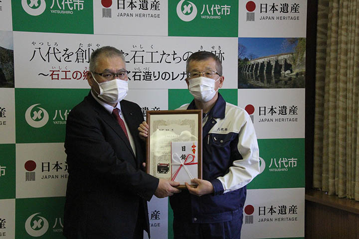 目録を手渡す日本道路建設業協会九州支部の森田支部長（左）