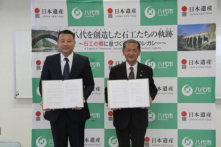 協定書を手にする岡村代表取締役（左）と中村市長